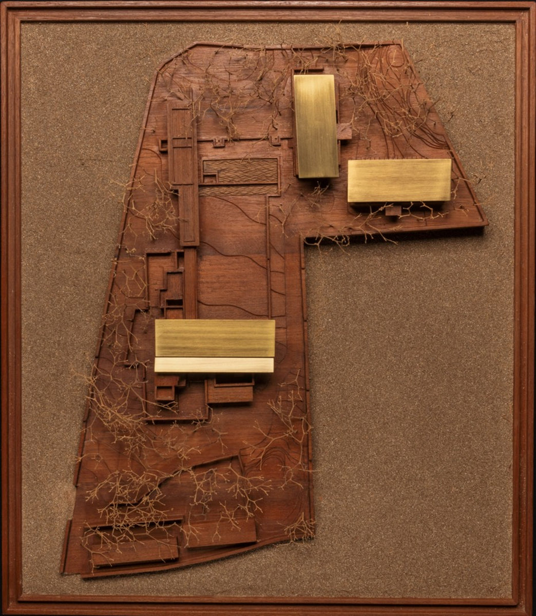 Physical site model seen from above, brass roof plates over a carved timber landscape