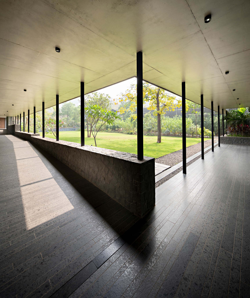 Deep verandah with a basalt parapet and black columns framing the garden beyond