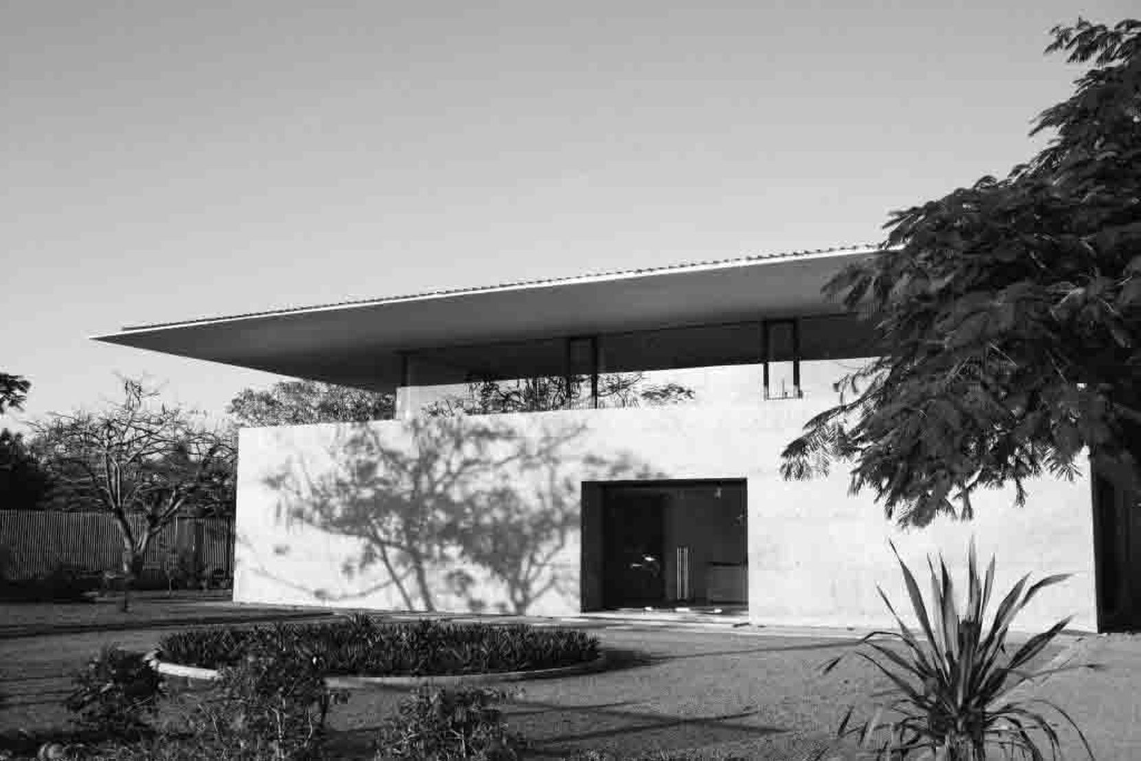 Front elevation in monochrome, the thin roof spanning above a plain wall and recessed entrance