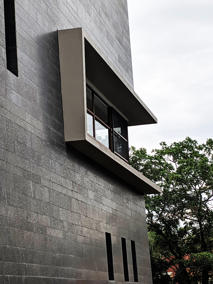 Cantilevered window box projecting from the coursed granite wall against a pale sky