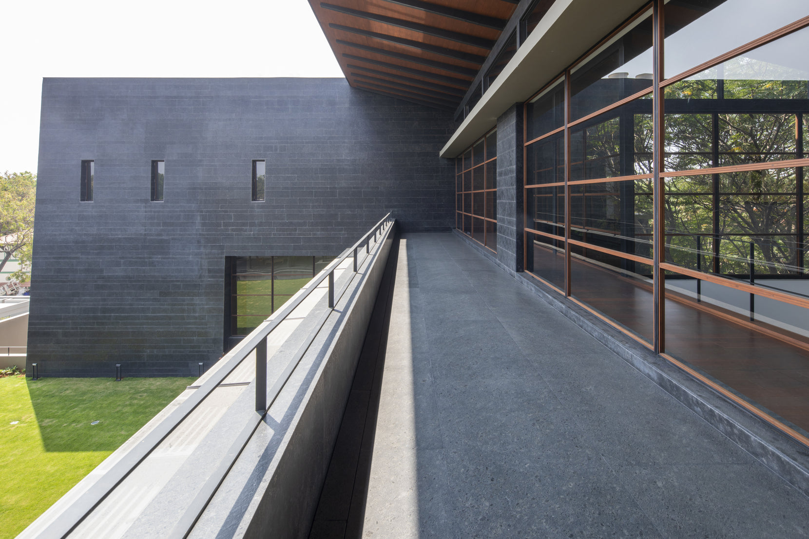 Narrow terrace between the granite bastion and the glazed upper storey, lawn dropping away