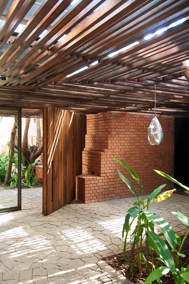 Brick Kiln House entrance under a timber rafter canopy, stepped brickwork beside a pivot door
