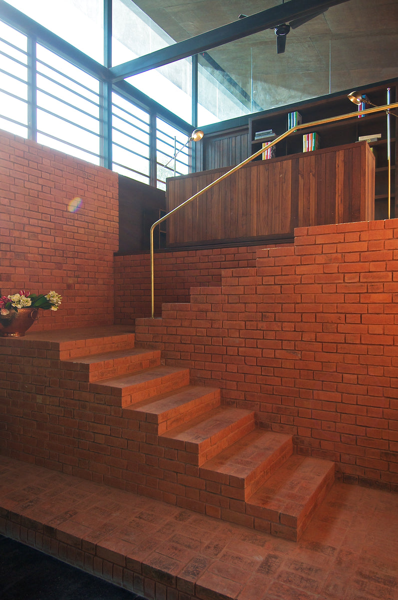 Brick stair rising to a timber-clad mezzanine under a long clerestory window