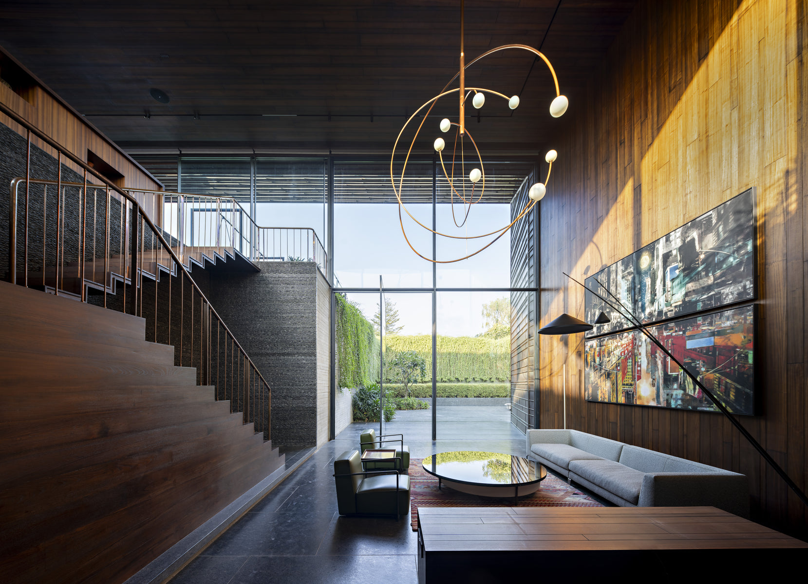 Double-height hall with a sculptural brass light and timber stair rising along the wall