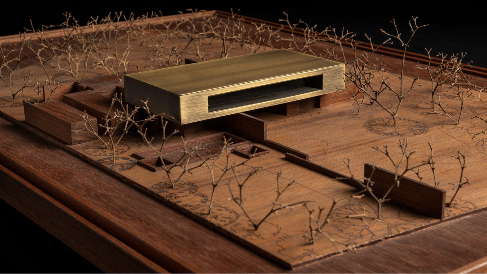 Scale model of Diya House, a brass slab set among wire trees on a carved timber base