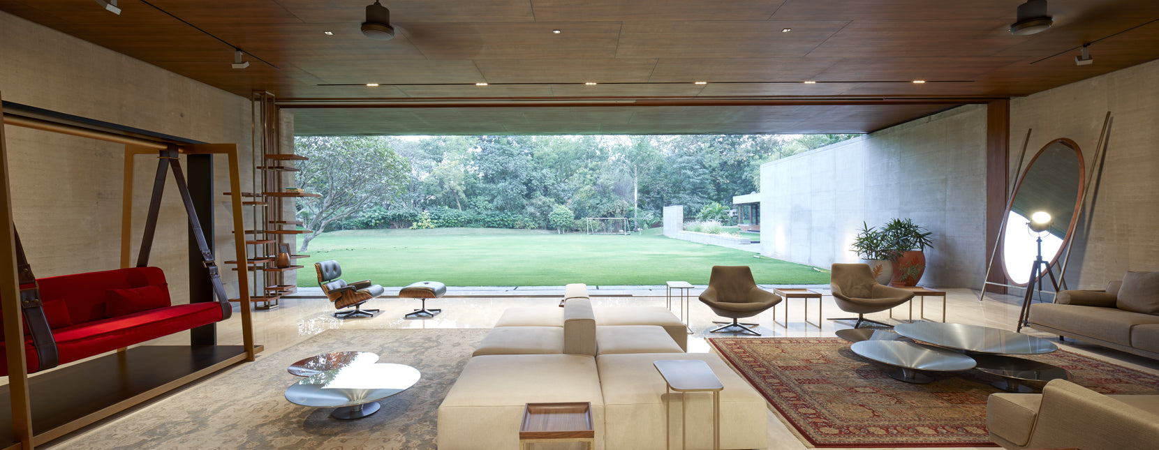 Living room opening full width to the lawn, with concrete walls and a timber ceiling