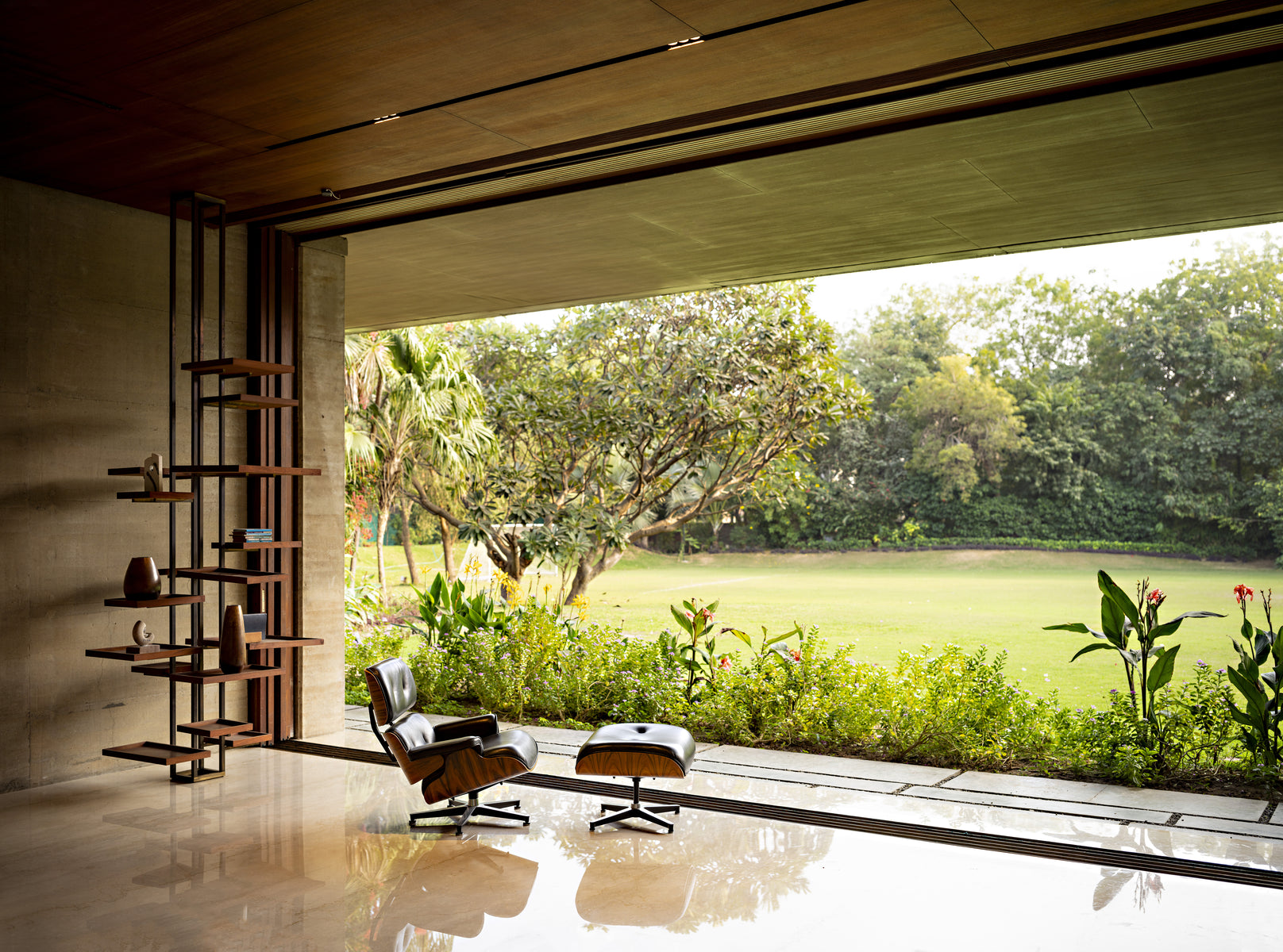 Lounge chair at the open corner, looking past the planting bed to the trees and lawn