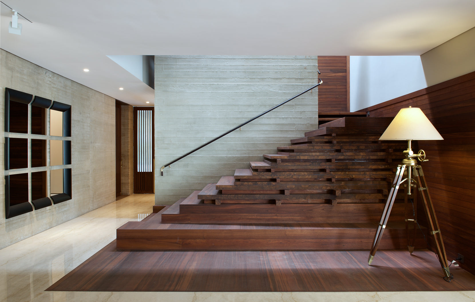 Broad timber staircase against a stone wall, with a slim black handrail