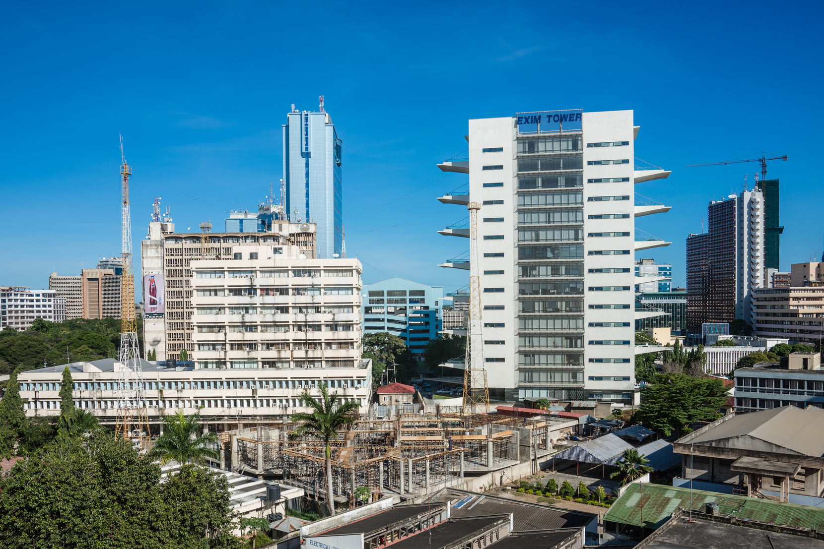 Tower standing among the central business district, cranes and low roofs all around