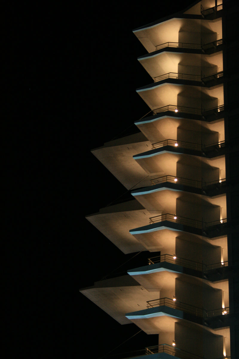 Terraces lit at night, the underside of each cantilever glowing against a black sky