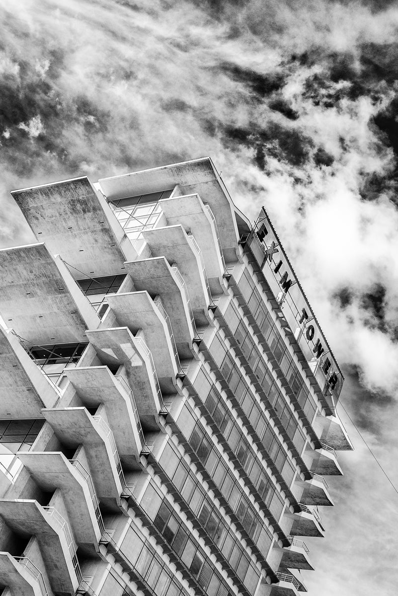 Tilted framing of the terrace stack and rooftop sign, cloud breaking behind