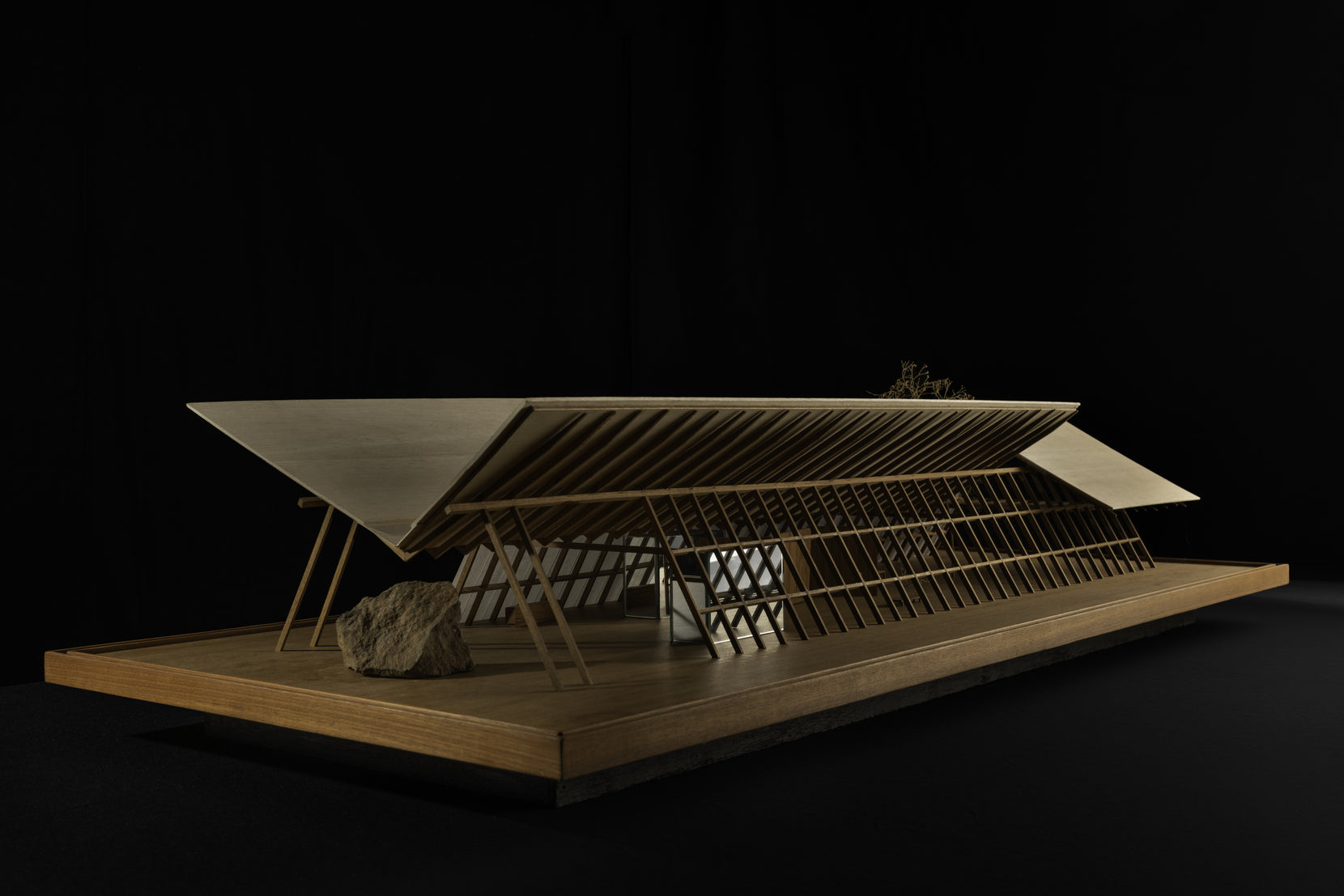 Physical model in timber, the roof cantilevering over a rock set beneath