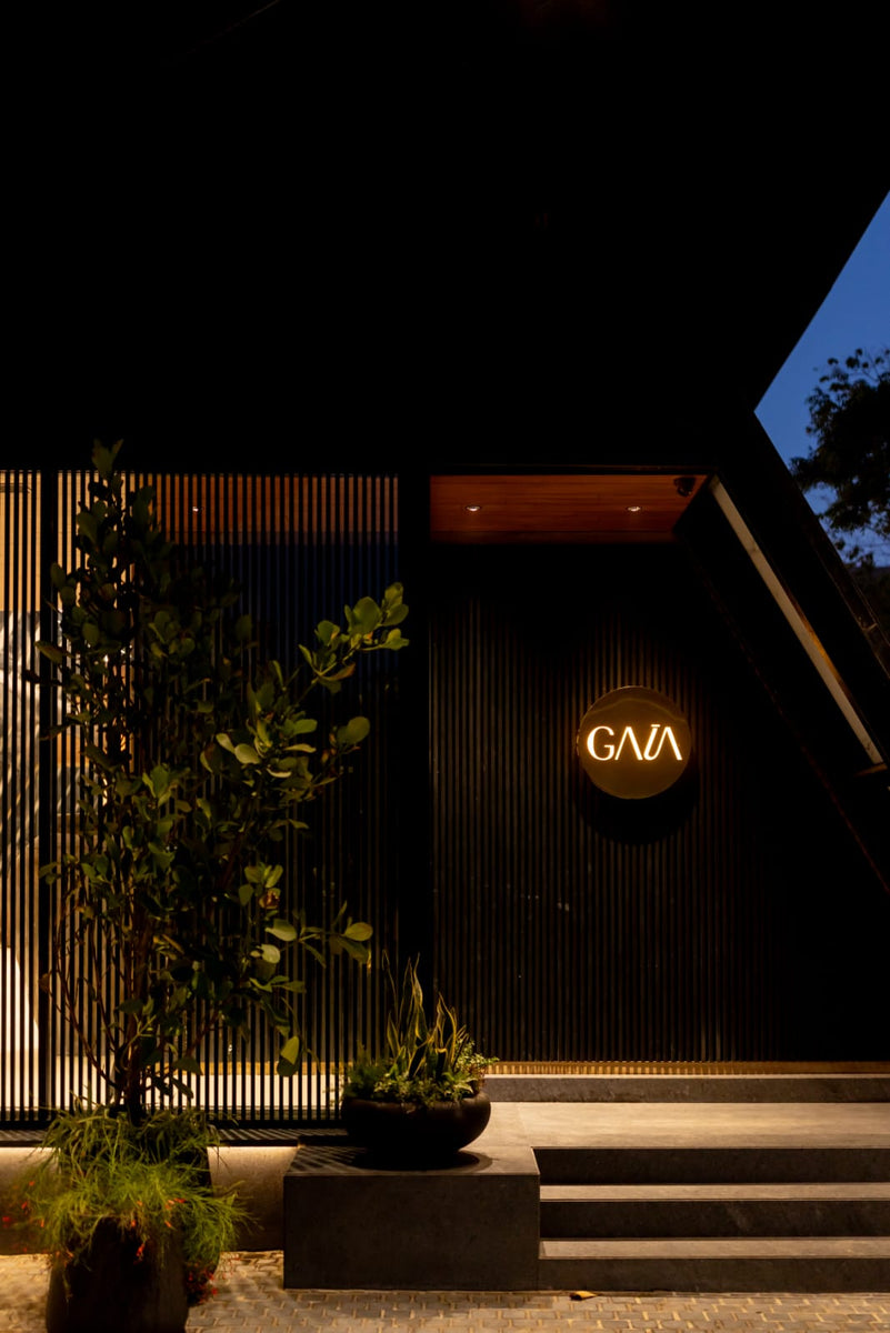 GAIA gallery entrance at night, illuminated roundel sign on a battened black wall