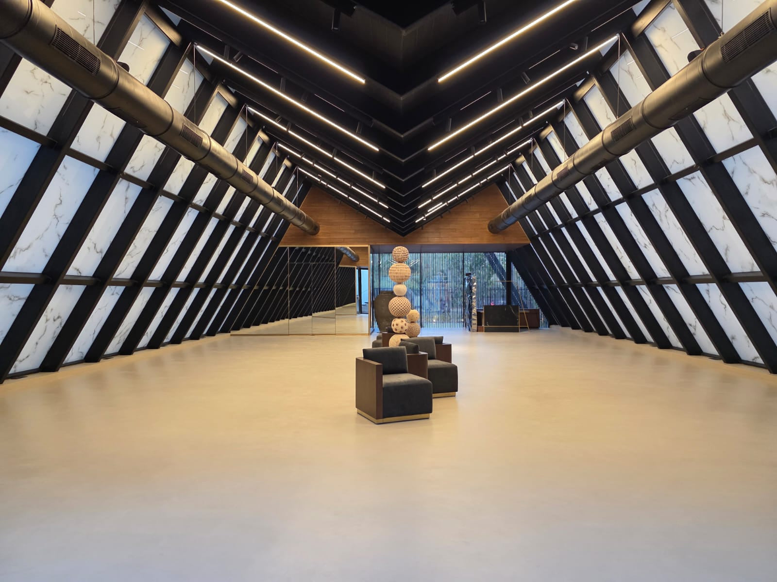 Gallery interior with sloping marbled glass walls braced by black steel and exposed ducting