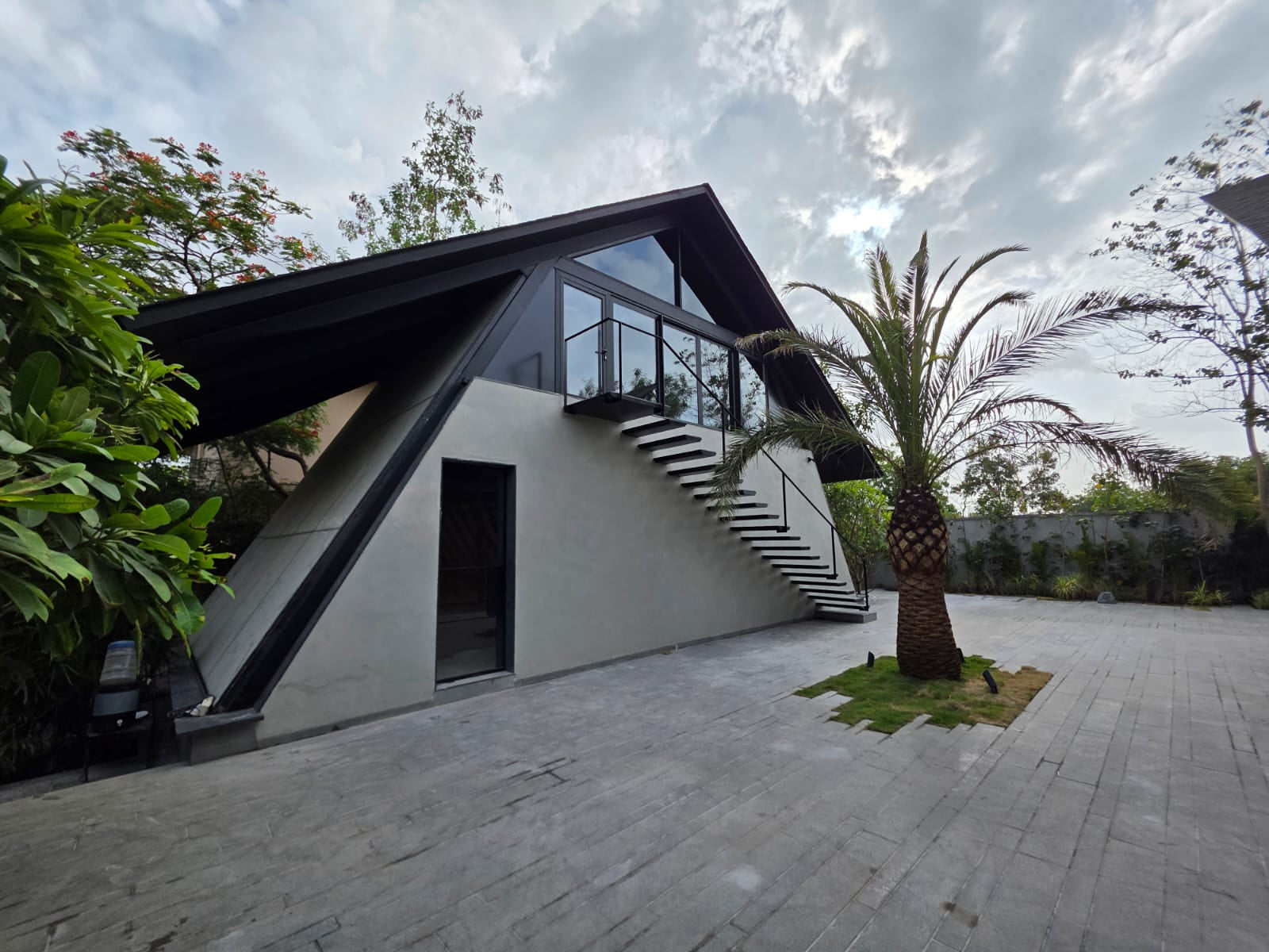 External stair climbing the rendered end wall to an upper glazed room, palm alongside