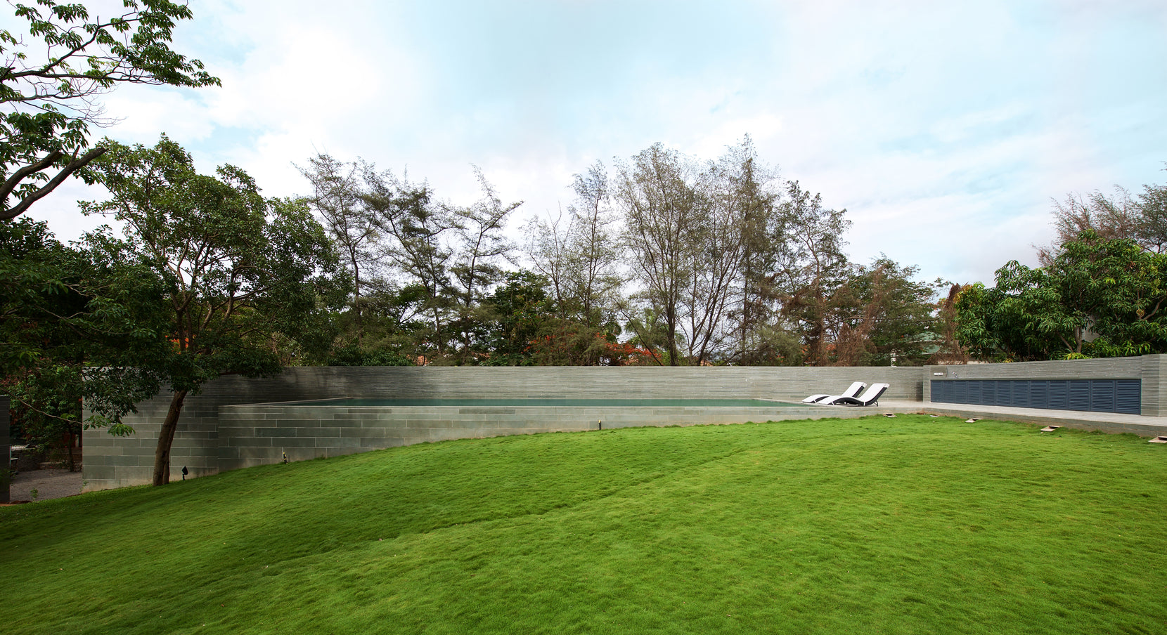 Grassed mound curving up to the stone retaining wall, with the pool terrace behind