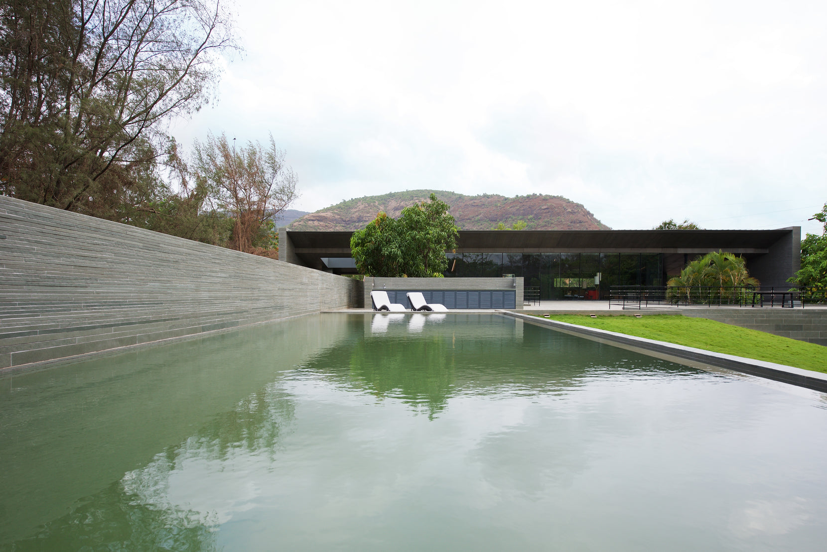 Hills reflected in the pool at Gomati, the house stretched low along the far edge