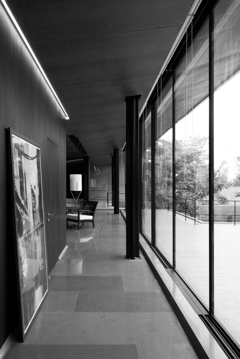 Glazed corridor with a large framed artwork resting against the panelled wall