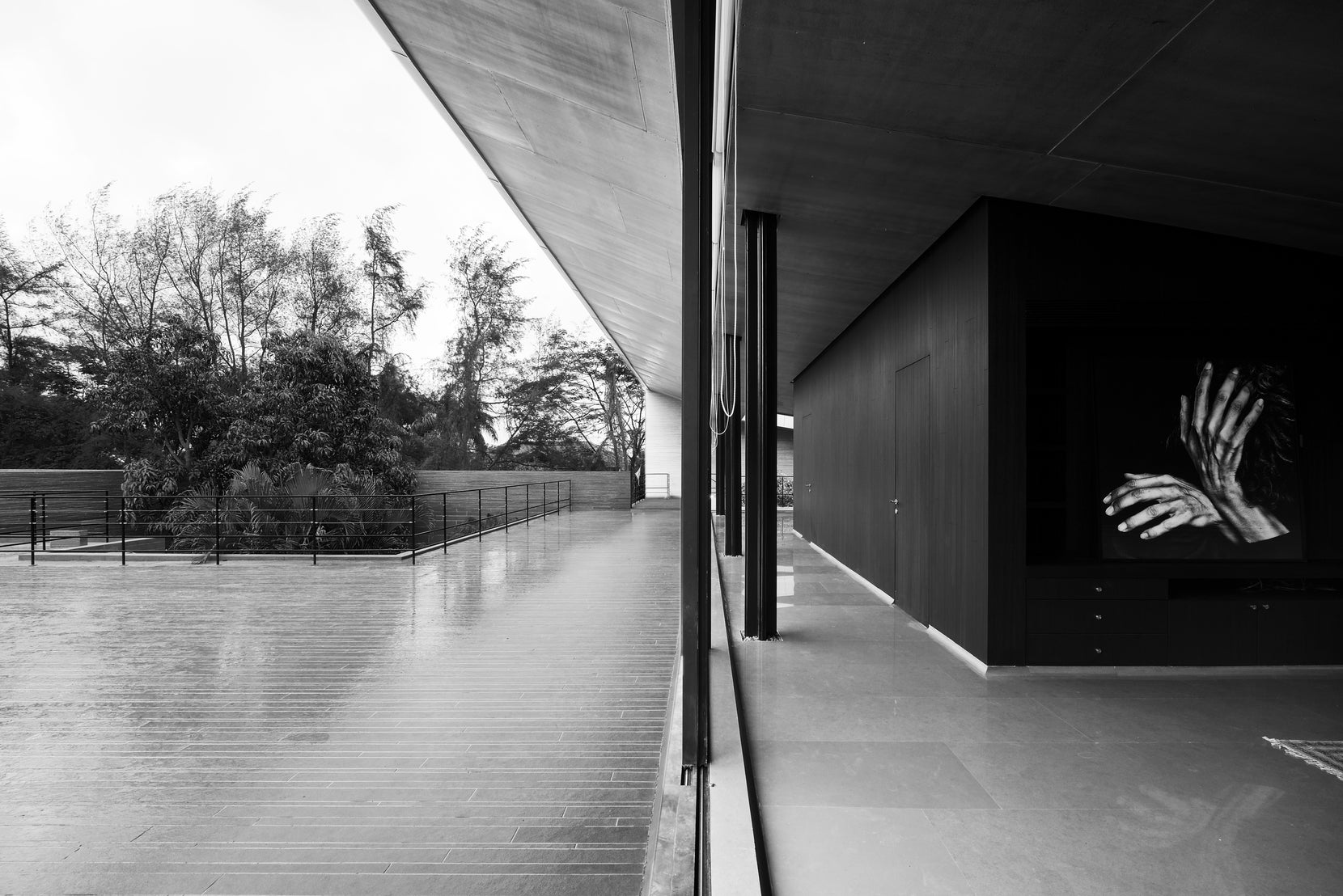 Wet terrace under the cantilever, a photograph of clasped hands on the dark interior wall