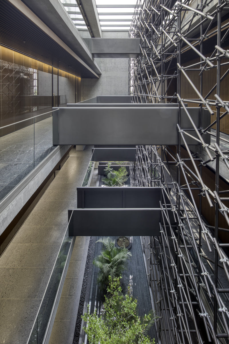 Steel bridges crossing the atrium above planted beds, tube screen to one side