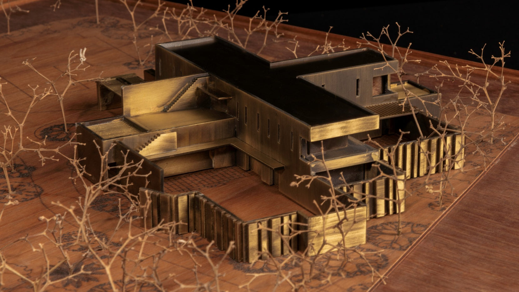 Study model viewed obliquely, brass volumes crossing over sunken courts among wire trees