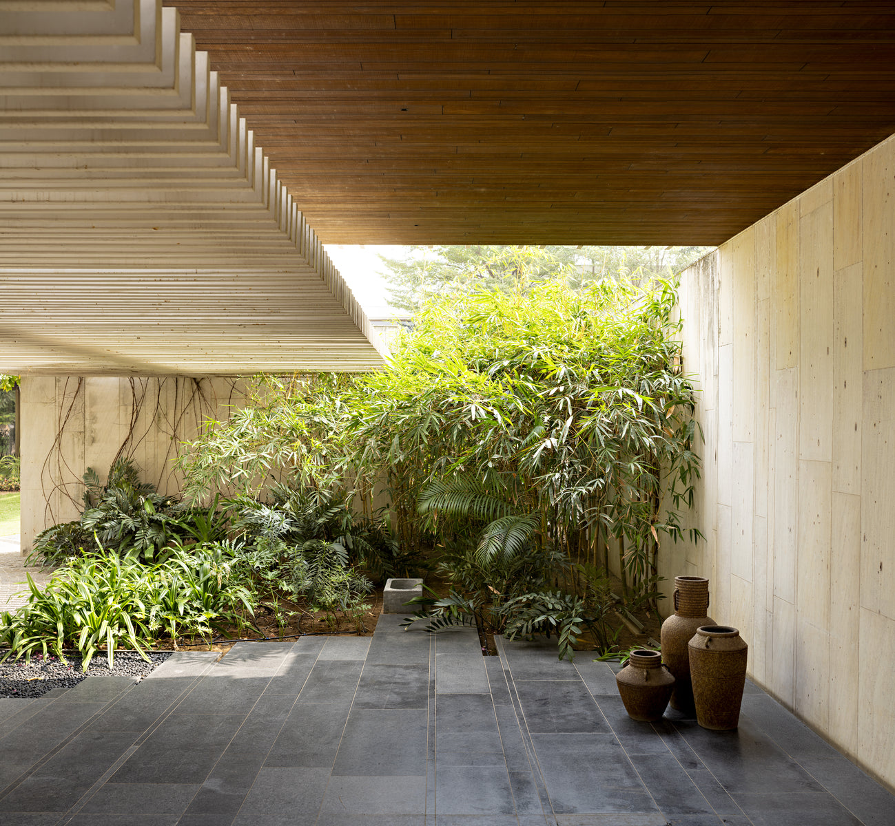 House of Secret Gardens, shaded undercroft opening onto a bamboo court with earthen urns