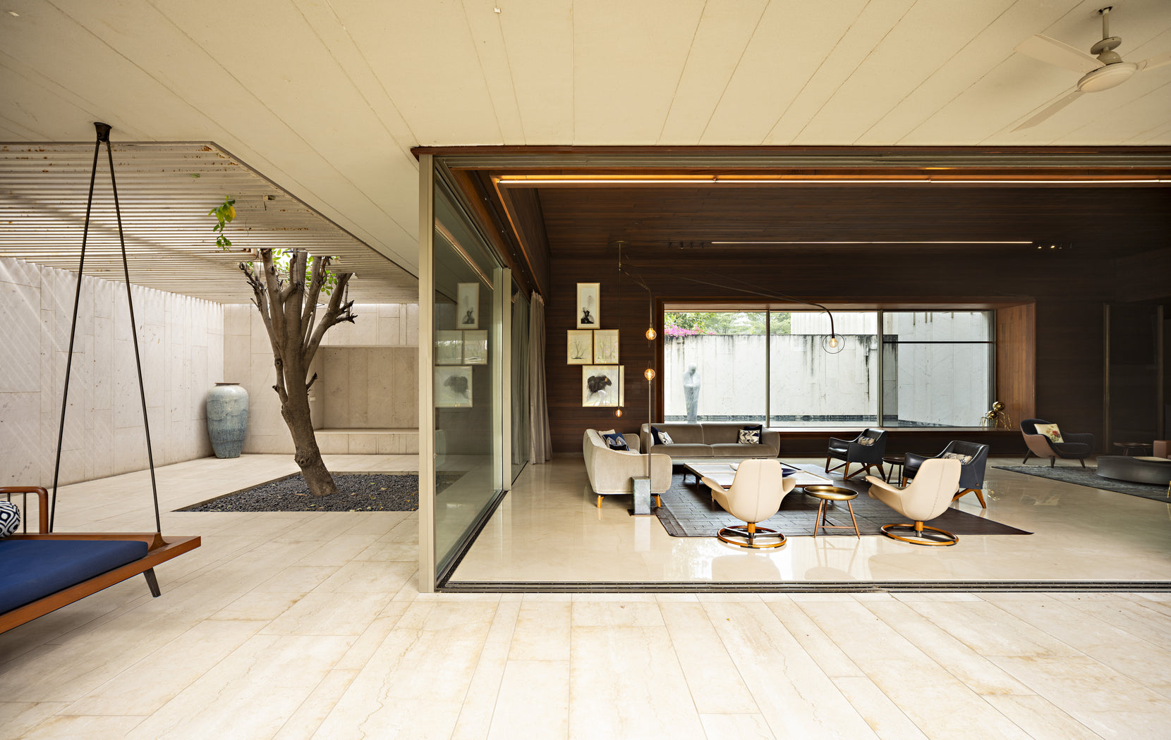 Swing seat on the terrace beside a courtyard tree, living room open through sliding glass