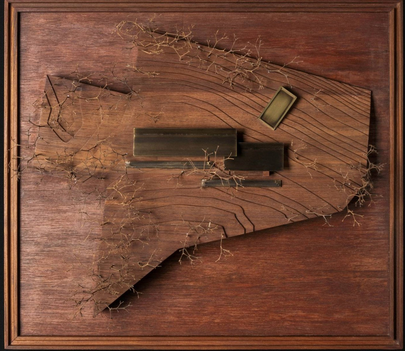 Framed site model from above, dark bars of the house laid along carved contours