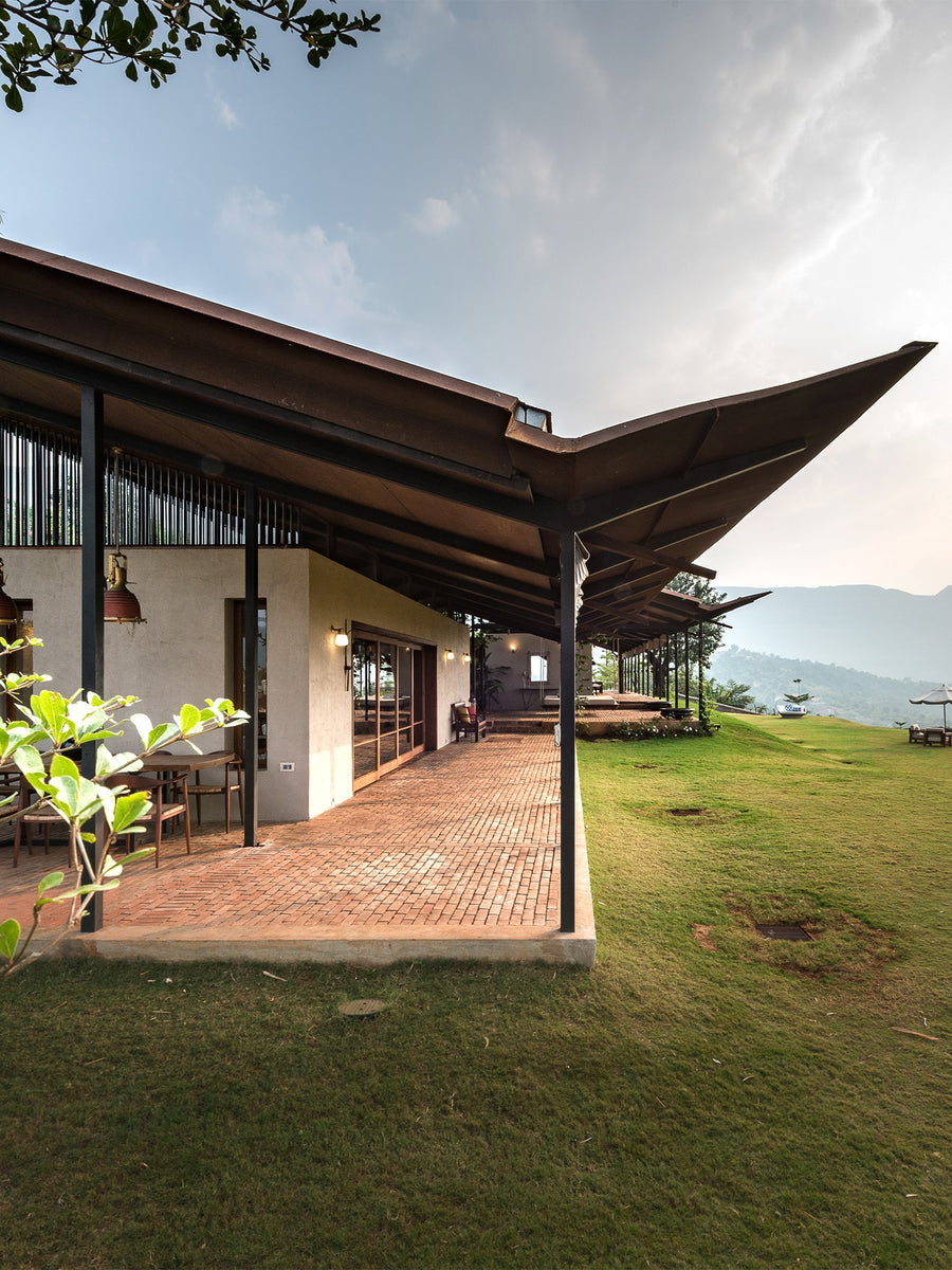 House with the Gabion: a folded metal roof over the brick verandah, hills to the east