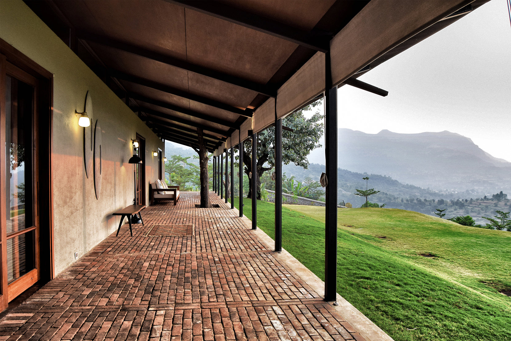Brick-paved verandah running the length of the house, hills framed between steel columns