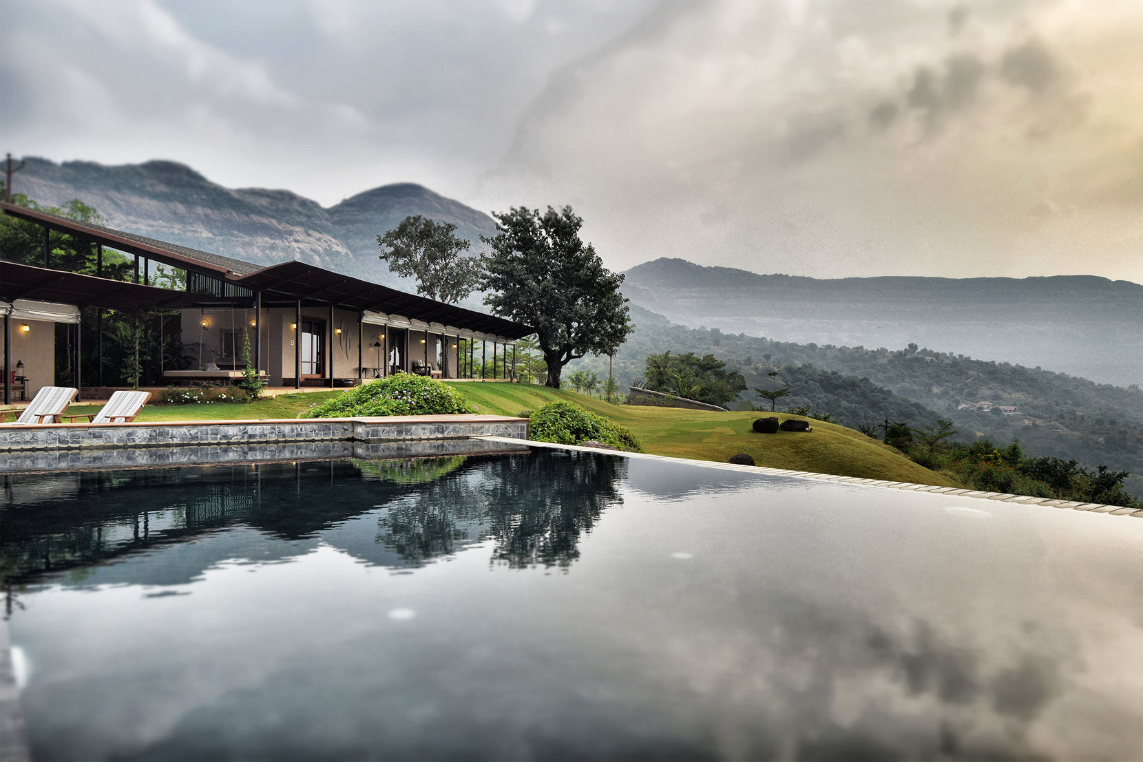 Long low profile of the Lonavala house mirrored in the infinity pool, Sahyadri hills beyond