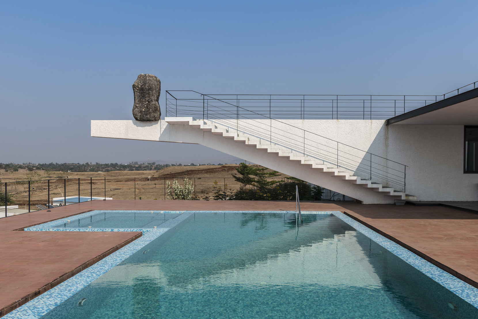 Straight stair rising to the rock-tipped cantilever above the terracotta pool terrace