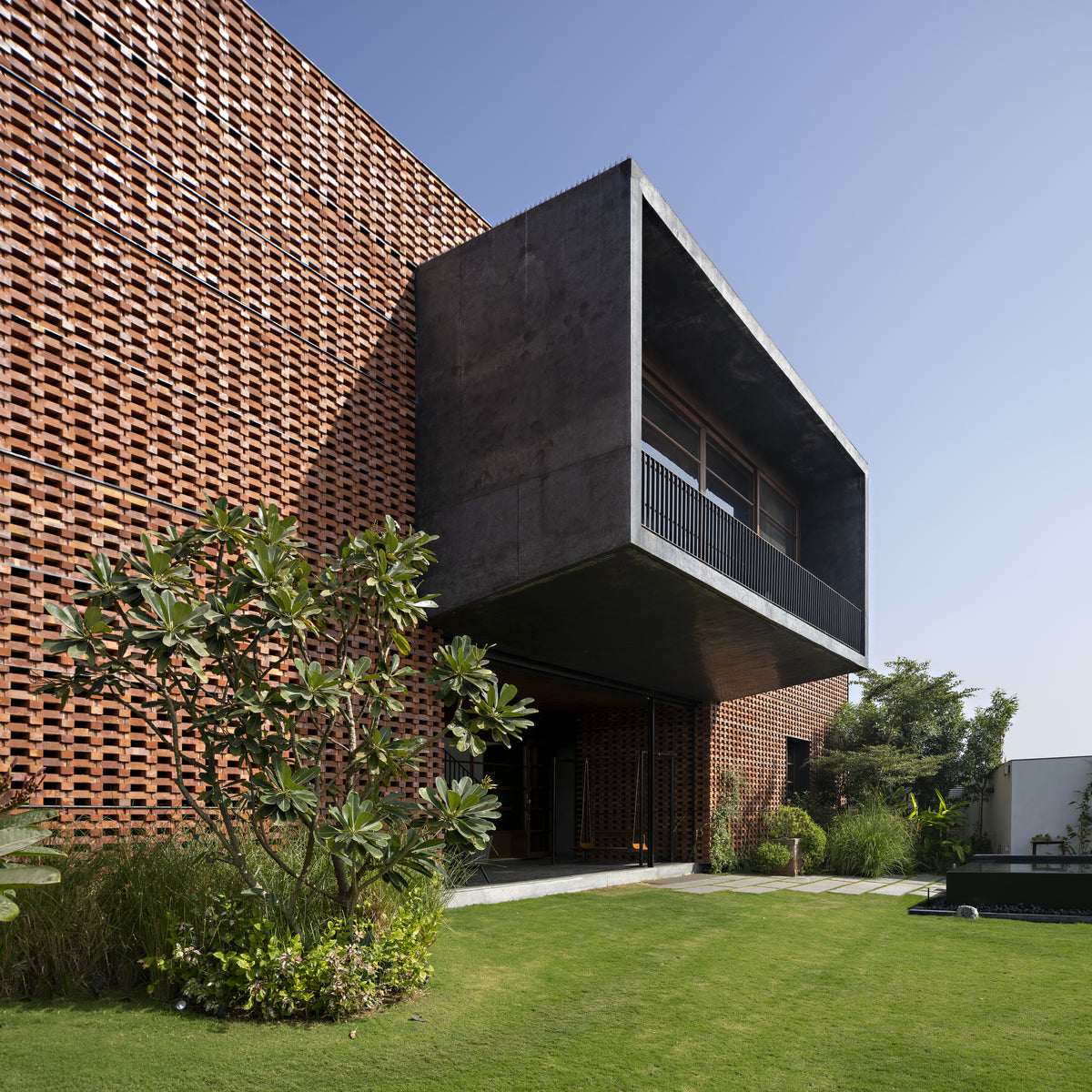 Ishtika in Ahmedabad, a dark concrete balcony box pushed out through the perforated brick veil