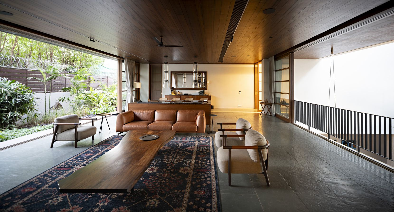 Living room with a teak ceiling, tan leather sofa and long timber table on a patterned rug