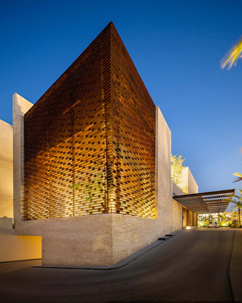 Ishtika house in Dubai at dusk, perforated brick lattice glowing above pale stone walls
