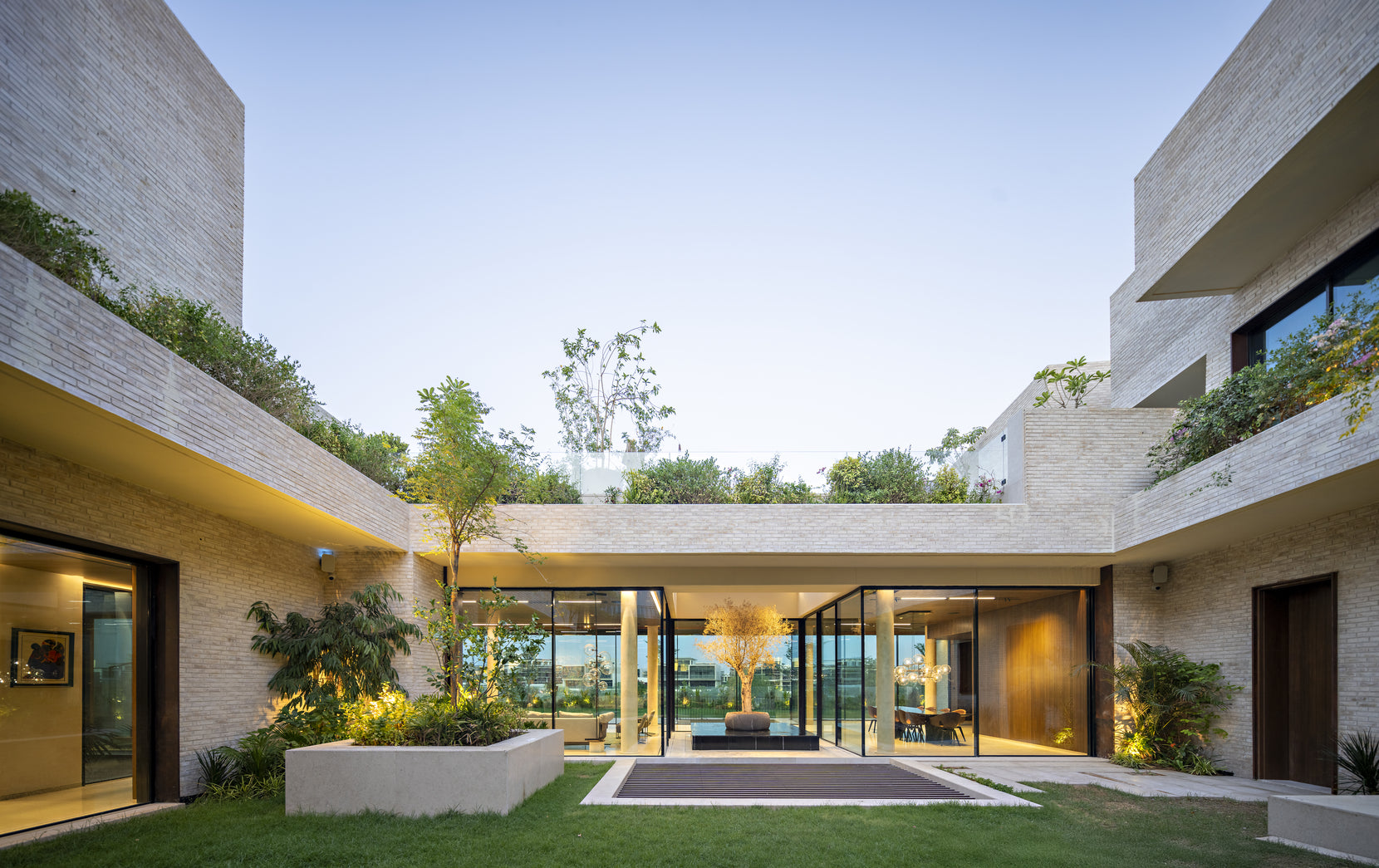 Ishtika's central courtyard framing a glazed living pavilion under planted roof edges