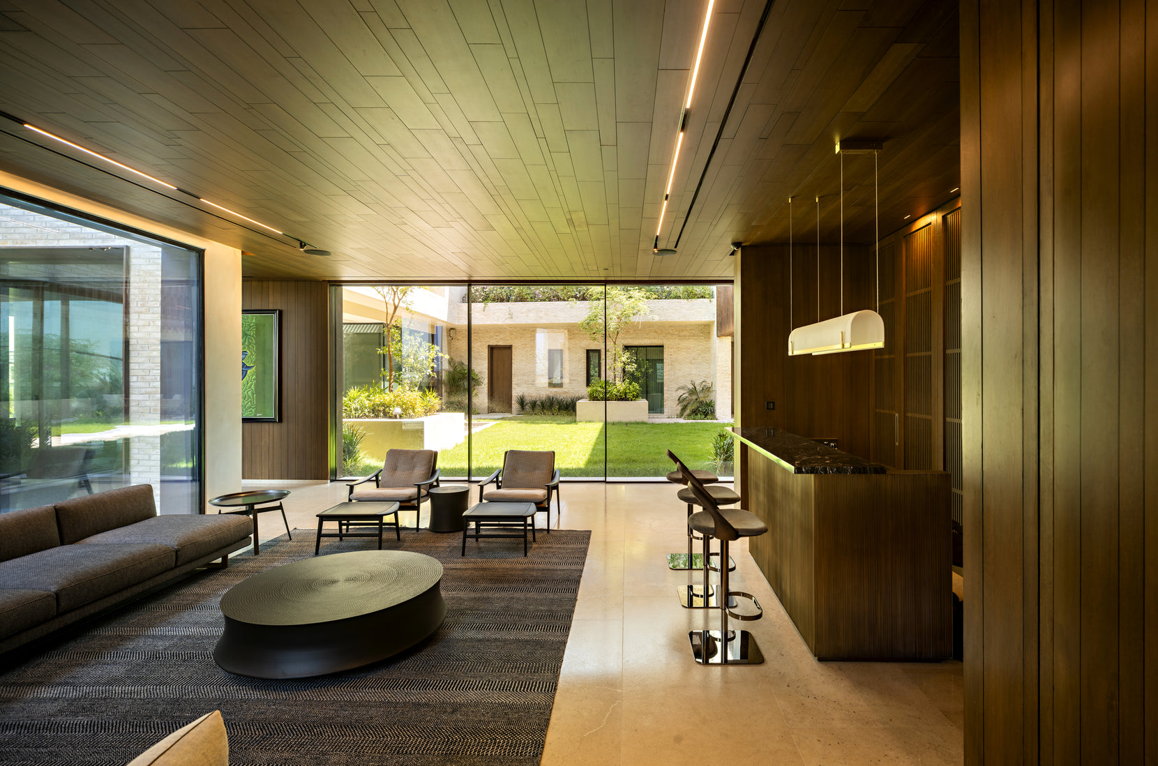 Living room lined in teak, bar counter to one side and sliding glass opening to the garden