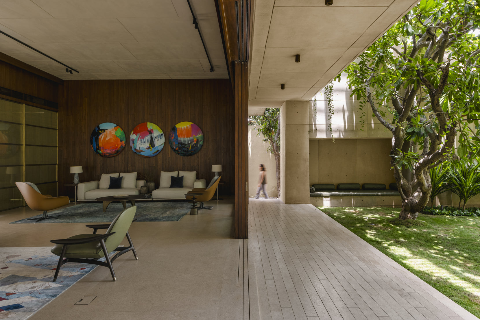 Living room opening onto the lawn, three circular paintings on the teak-panelled wall
