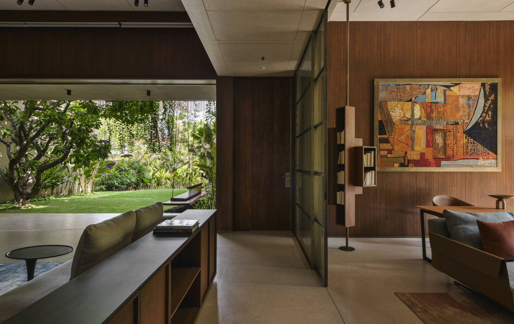 Sitting area with a steel-framed glass partition, abstract painting and a low sill opening to the garden