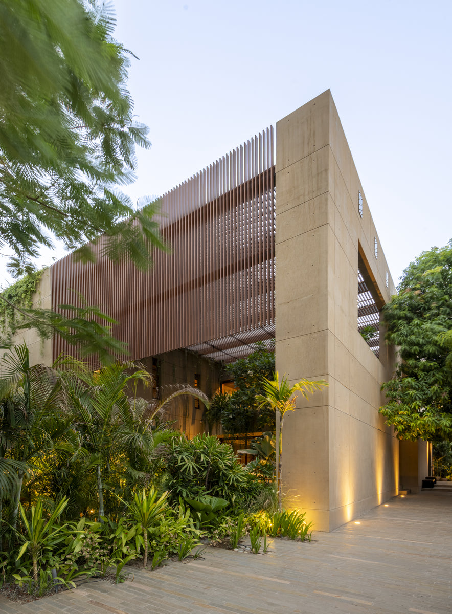 Kasaya at dusk, its timber louvred screen cantilevered beside a concrete pier over uplit planting