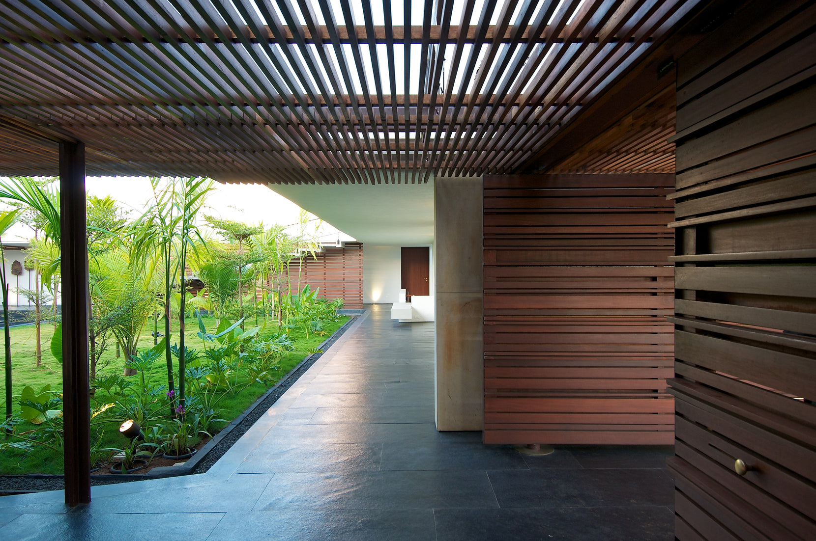 Khadakvasla House verandah under a timber lattice, opening to the planted courtyard