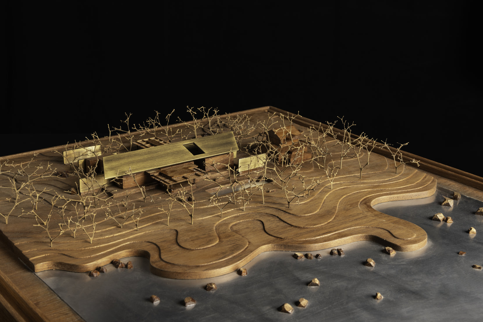 Scale model of the site, the brass house set on carved timber contours beside a metal lake