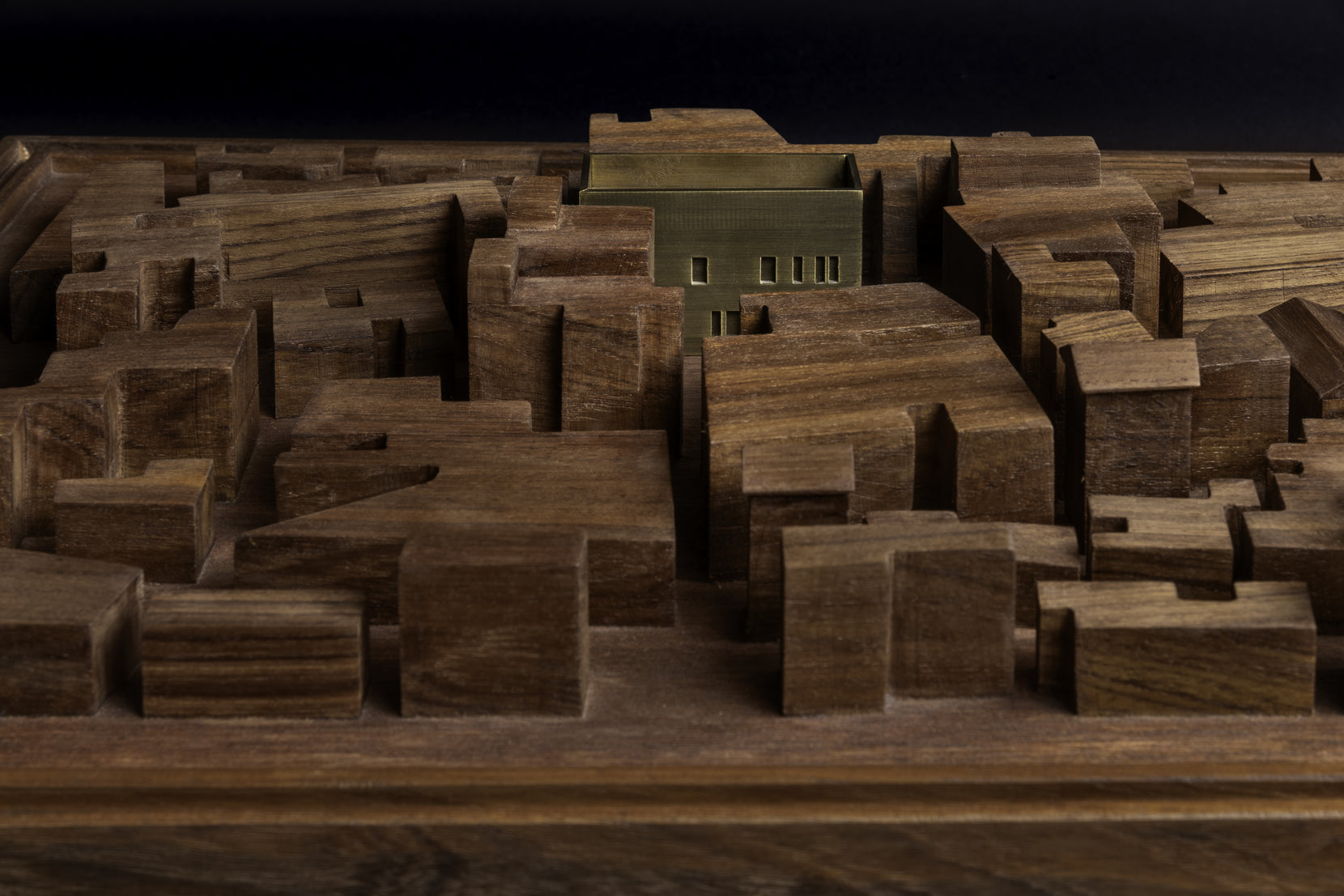 Brass block of the house standing among the timber massing of the surrounding buildings