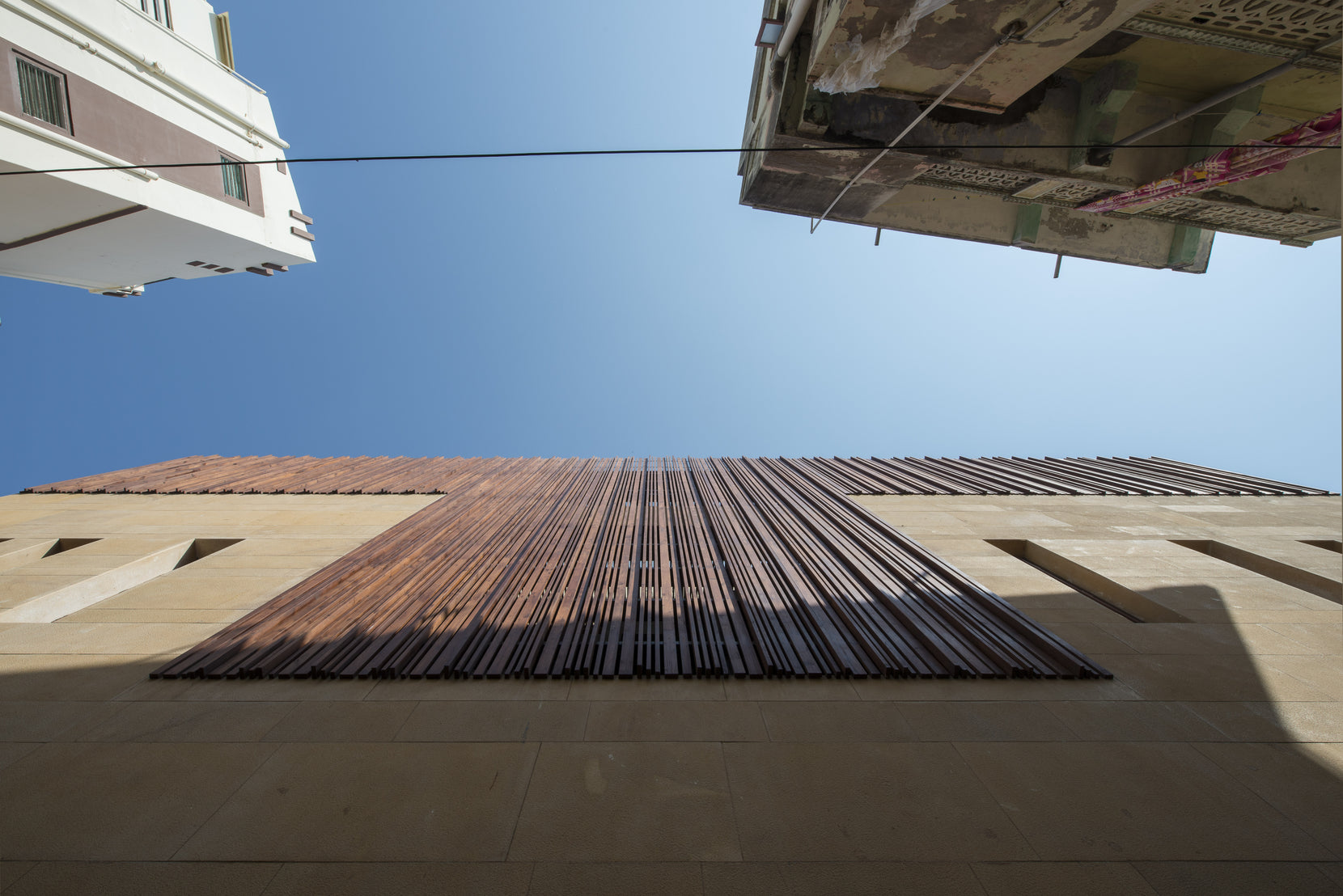 Timber screen crowning the house, seen straight up from the narrow lane between neighbours