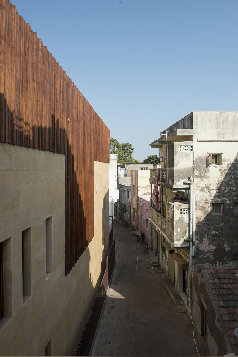 Narrow Mandvi lane with the timber-clad flank of the house facing weathered older buildings