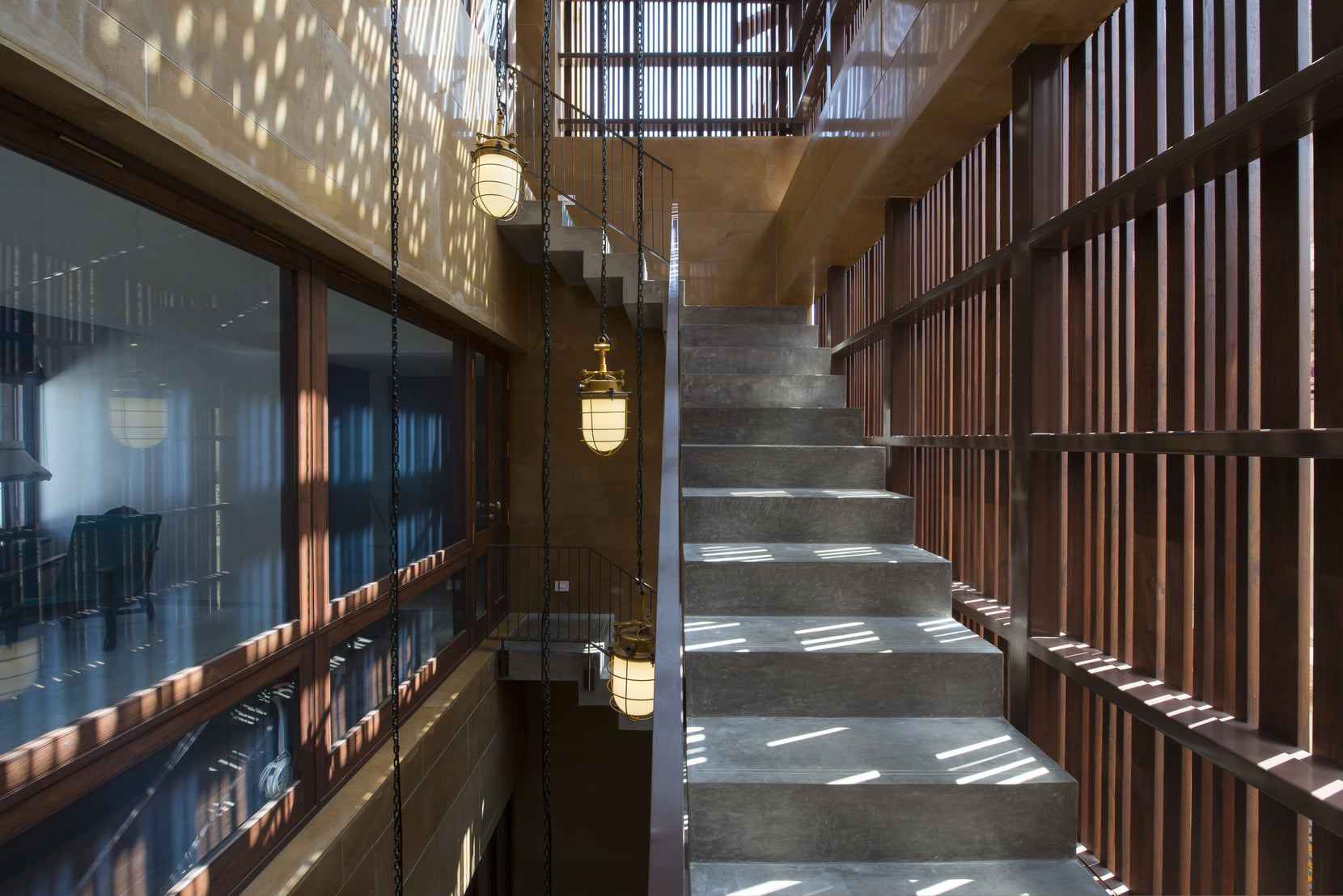 Concrete stair beside a timber slat screen, dappled light falling from the grille above