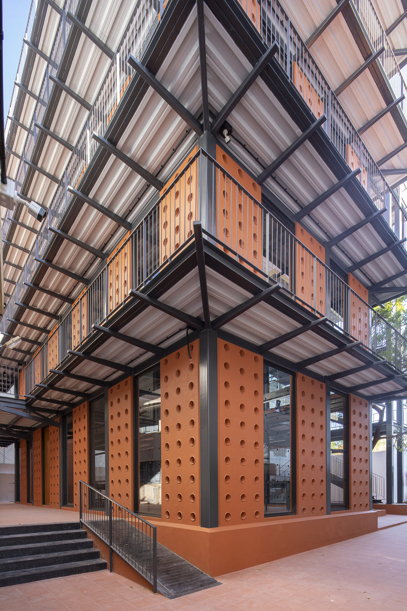 Corner of the building looking up past stacked steel balconies and perforated terracotta panels