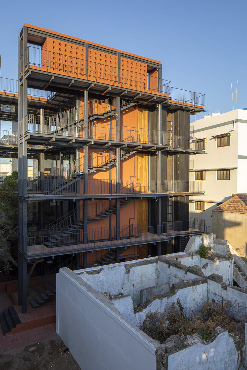 Full stack of open stair landings lit by low evening sun, a ruined wall in the foreground
