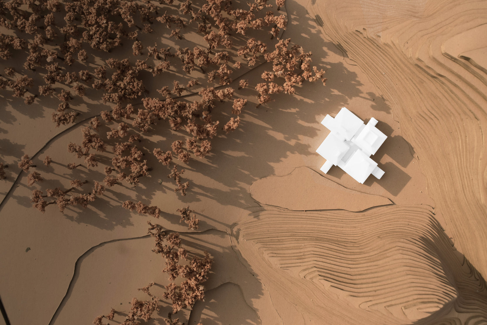 Scale model from above, white blocks on modelled sand terrain beside an oasis of trees