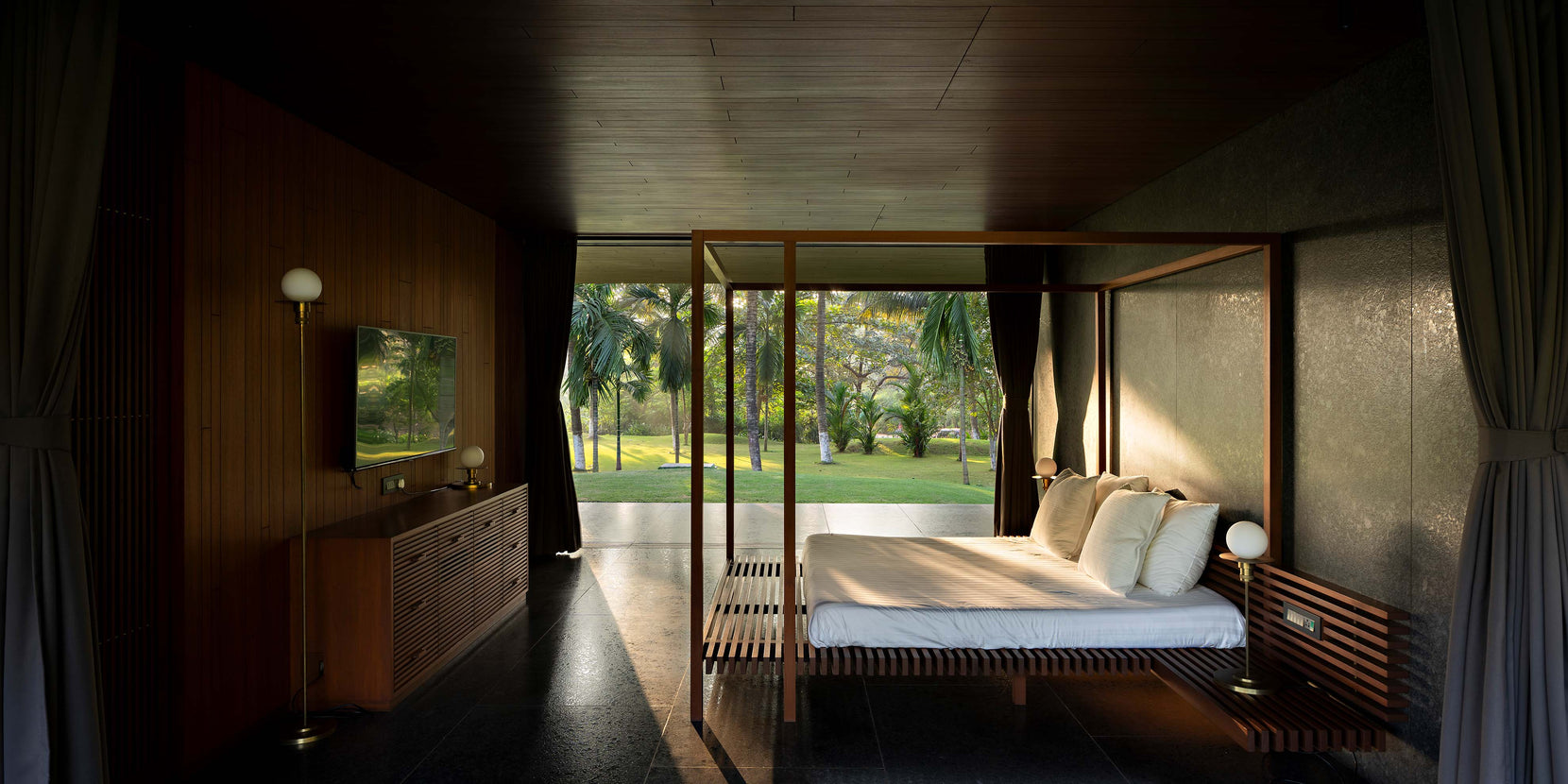 Bedroom with slatted teak bed and full-height glazing opening to the coconut grove
